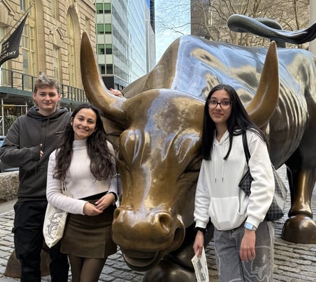 Students standing in front of a bronze bull during their visit to Wall Street on their New York trip.